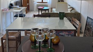 Comedor con mesa preparada para cuatro, un ventilador, una lámpara y vista al exterior a través de una ventana.