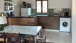 Cocina compacta con comedor, vigas de madera, lavadora y salpicadero de azulejos.