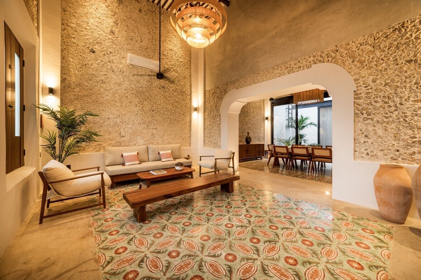 Un vaste espace de vie agrémenté d’un mur en pierre, d’un canapé, d’une table basse et d’un coin repas avec des chaises.