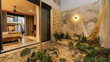 Un intérieur moderne avec un lit, un hamac et un petit espace jardin.