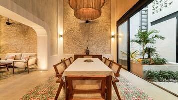 Un espace repas avec une longue table, des chaises et un mur à la texture particulière.