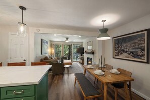 Eine moderne Küche mit einer Marmorinsel, einem Holzesstisch und einem Kamin.