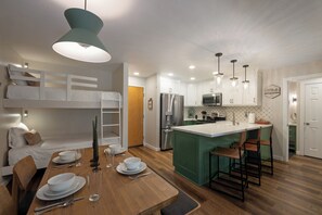 Eine moderne Küche mit einer zentralen Kochinsel, integrierten Geräten und einem Essbereich mit Holztisch und Stühlen.