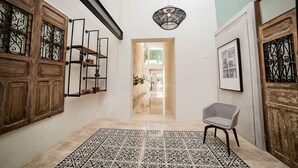 Un pasillo con un tapete estampado, una silla y un cuadro en la pared.
