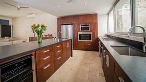 Una cocina moderna con una isla central, hornos integrados y un amplio ventanal.