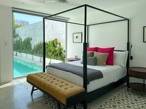 Ein modernes Schlafzimmer mit einem Himmelbett, einer Bank und Blick auf einen Swimmingpool.