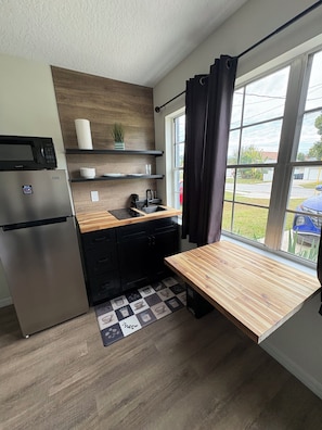 A compact kitchen with a refrigerator, microwave, sink, and wooden countertop. - Tranquil 1-bedroom apartment with AC in vibrant Orlando (Orlando)