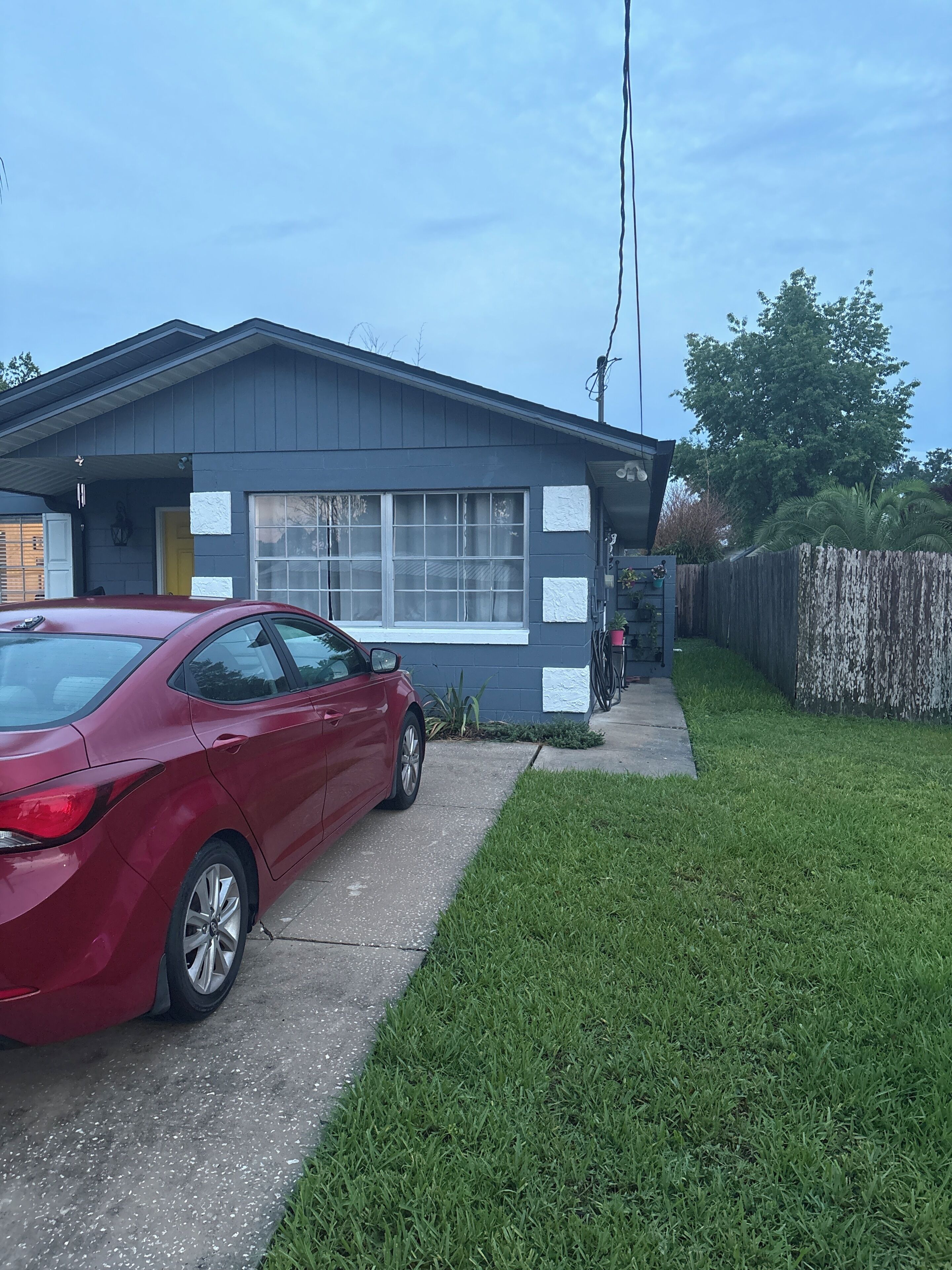 A residential house with a garage, a red car parked in front, and a well-maintained lawn.