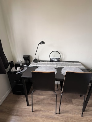 A small, neatly arranged room with a table, chairs, a coffee maker, a lamp, and a mirror. - Tranquil 1-bedroom apartment with AC in vibrant Orlando (Orlando)