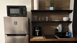 Een kitchenette met een roestvrijstalen koelkast, een magnetron, een koffiezetapparaat en een spoelbak.