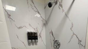 Een douche met marmeren wanden en een vloer met een honingraatpatroon.