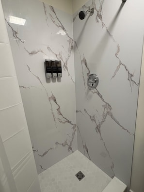 A shower with marble walls and a hexagonal floor pattern. - Tranquil 1-bedroom apartment with AC in vibrant Orlando (Orlando)