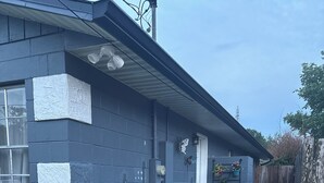 Een huis met een blauwe gevel, een betonnen pad en een houten omheining.