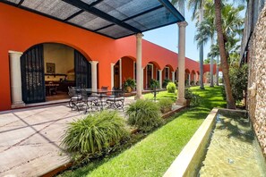 A courtyard with a glass table and chairs, surrounded by palm trees and a water feature. - Family 3 bdrm Hacienda House in Centro (Centro)