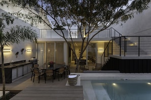 A modern outdoor patio with a pool, dining area, and a staircase leading to an upper level. - Casa Naranjas · Design Home · Pool & Jacuzzi (Merida)