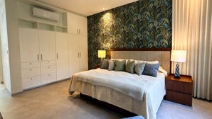 Een slaapkamer met een bed, nachtkastjes, een garderobe en een decoratieve wand.