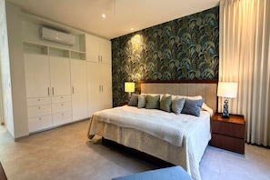 A bedroom with a bed, nightstands, a wardrobe, and a decorative wall. - Casa Naranjas · Design Home · Pool & Jacuzzi (Merida)