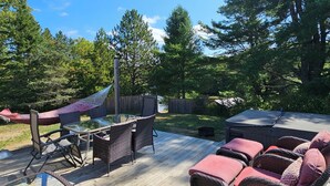 A wooden deck with wicker furniture, a hammock, and a glass table. - FALLS VIEW HAVEN (Gilmour)