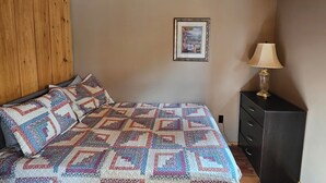 A bedroom with a wooden ceiling, a ceiling fan, a bed with a quilt, a dresser, and a framed picture on the wall. - FALLS VIEW HAVEN (Gilmour)