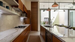 Eine moderne Küche mit Marmorarbeitsplatte, Holzschränken, einem Gasherd und Pendelleuchten.
