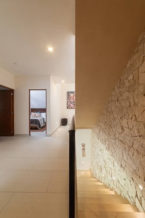 Ein modernes Interieur mit einer Steinwand, einer Treppe und einem Schlafzimmer im Hintergrund.