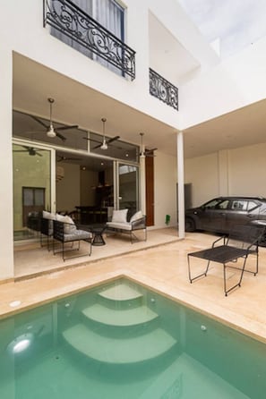 Ein modernes Haus mit Swimmingpool, Sitzgelegenheit im Freien und einem geparkten Auto.