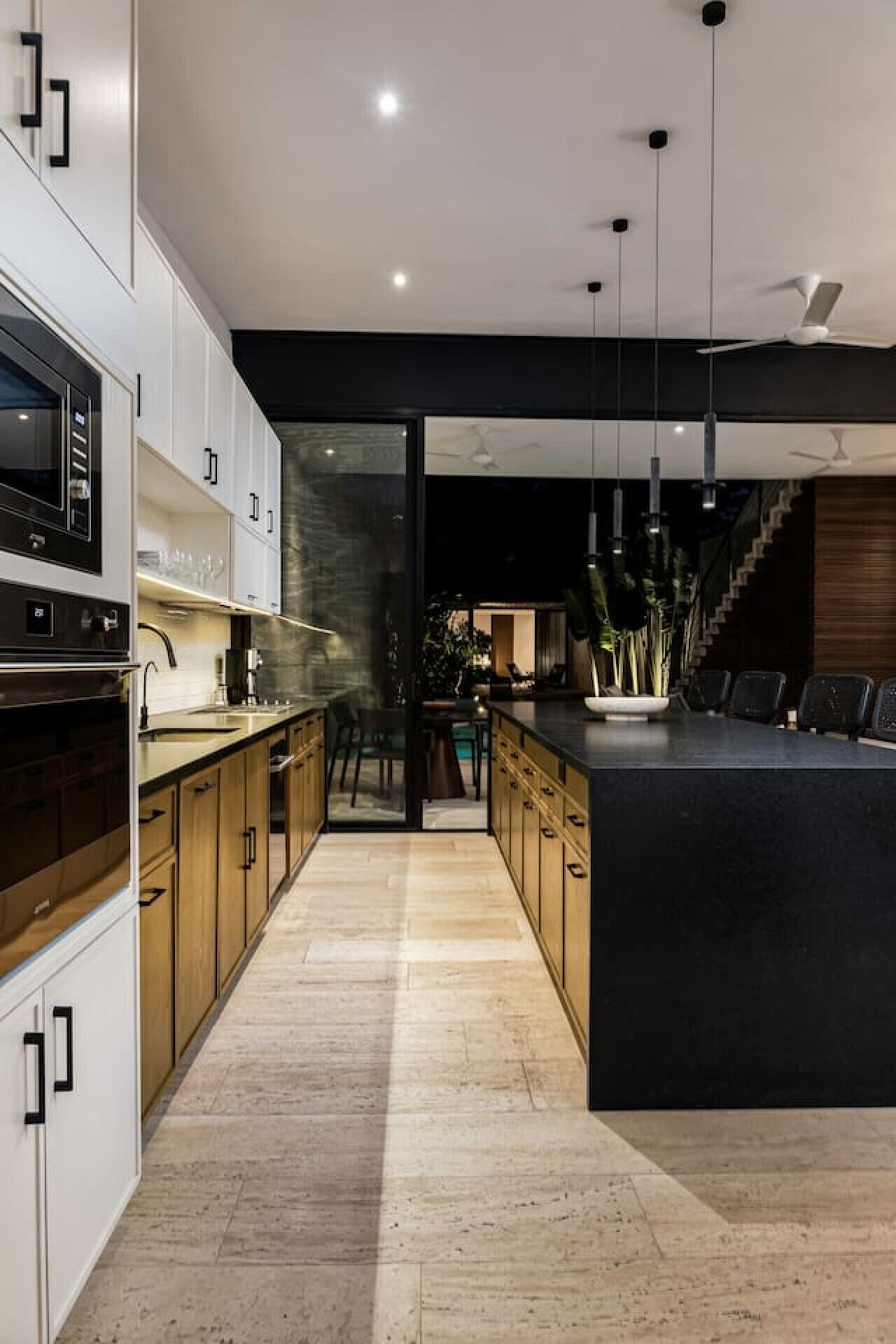 A modern kitchen with a central island, built-in appliances, and a staircase leading to an upper level.