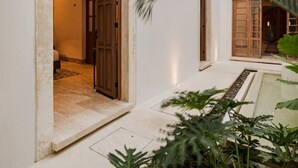 Een modern gebouw met een grote houten deur, een kleine binnenplaats en een palmboom.