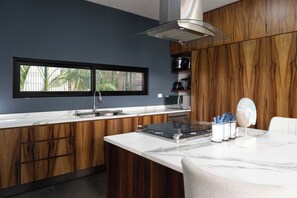 Eine moderne Küche mit Fenster, Holzschränken, einer Mikrowelle und einer Marmorarbeitsplatte.