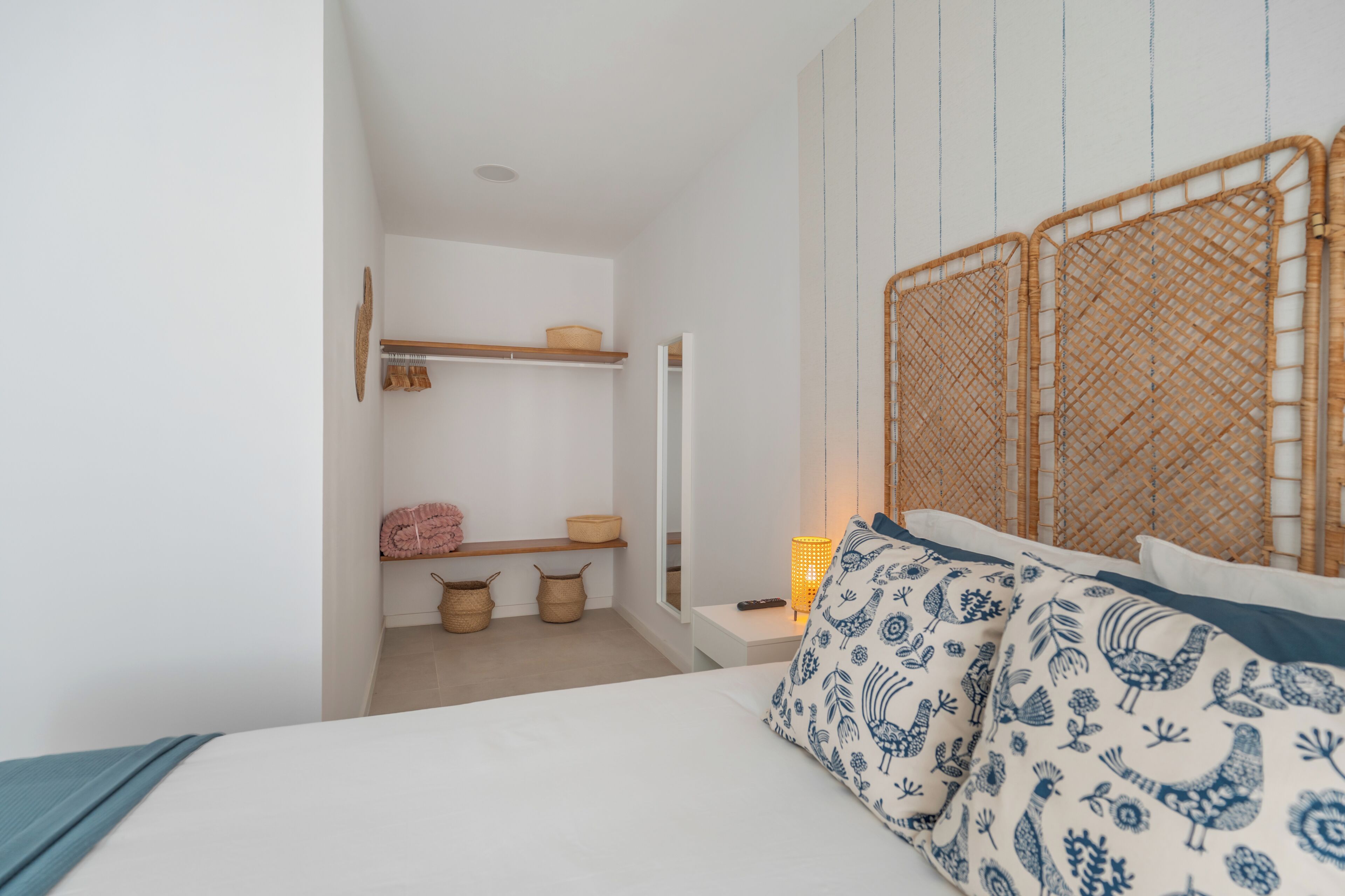 A bedroom with a bed, a bedside table, a lamp, and a wardrobe.