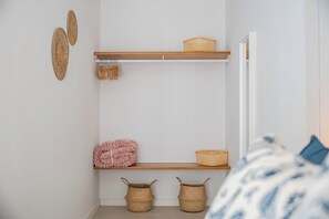 A bedroom with a bed, a shelf with baskets, a pink blanket, and a door. - 2-bedroom Apartment in Guargacho, Sur Tenerife (Arona)