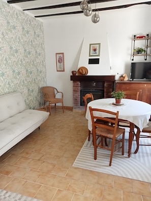 En stue med sofa, spisebord, stole, pejs og fjernsyn.