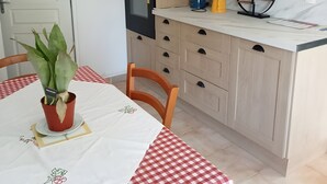 Eine Küche mit Holzausstattung, einem eingebauten Ofen und einem Esstisch mit kariertem Tischläufer.