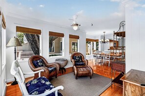 Ein geräumiges Zimmer mit Korbstühlen, einem Esstisch und einem Deckenventilator.
