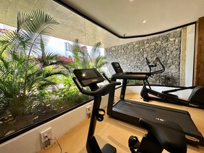A home gym with treadmills, a stationary bike, and a large window overlooking a garden. - Jardines Acoran Penthouse with Jacuzzi, Palm Mar (Palm-Mar)