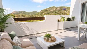 Een modern terras buiten met een bank, een tafel en uitzicht op een glooiend landschap.