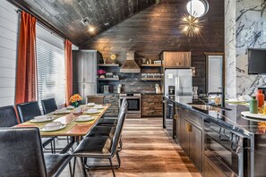Eine moderne Küche mit Essbereich, Holzboden und einer großen Kochinsel mit Spüle.