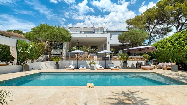 A swimming pool with lounge chairs and umbrellas, surrounded by greenery and a modern building. - Villa "les alizés" garden side, close to the sea (Saint-Raphaël)