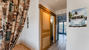 Een gang met een houten deur, een betegelde vloer en een muur met een schilderij van een busje.