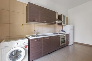 Eine kleine Küche mit Waschmaschine, Herd und Kühlschrank.