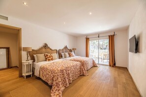 A bedroom with two beds, a television, and a sliding glass door to the outside. - MASTRU BELLU (BONIFACIO)