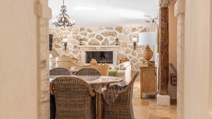 An interior with a stone wall, a fireplace, wicker furniture, and a tiled floor. - MASTRU BELLU (BONIFACIO)