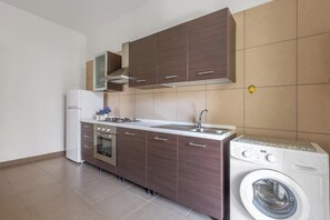 Une cuisine moderne équipée d’un four encastré, d’un lave-linge et d’un évier.