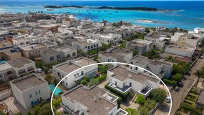 Luftaufnahme einer Küstenstadt mit Gebäuden, blauem Meer und Booten.