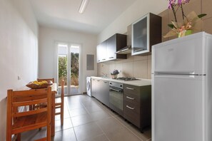 Eine moderne Küche mit Einbauofen, Kühlschrank und Essbereich mit Holztisch und Stühlen.