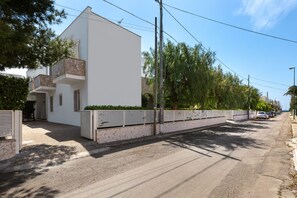 Ein modernes Gebäude mit weißer Fassade, Steinverzierungen und einem Balkon.
