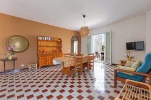 Ein Essbereich mit kariertem Boden, einem Holztisch mit Stühlen, einem Bücherregal und einem Fernseher.