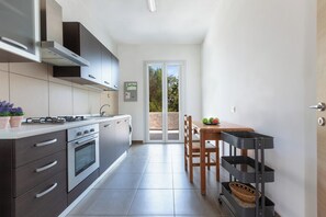 Eine moderne Küche mit Gasherd, Backofen und einer Essecke mit Tisch und Stühlen.