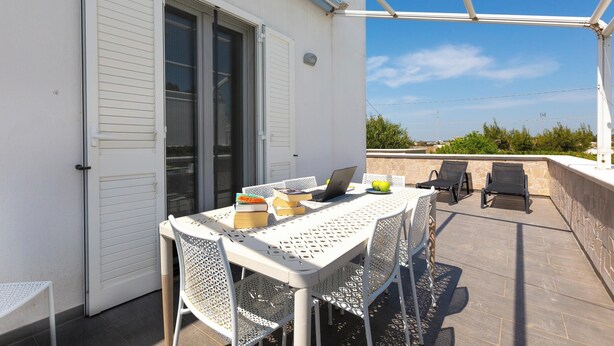 Eine Terrasse mit Tisch, Stühlen, einem Laptop und Büchern.