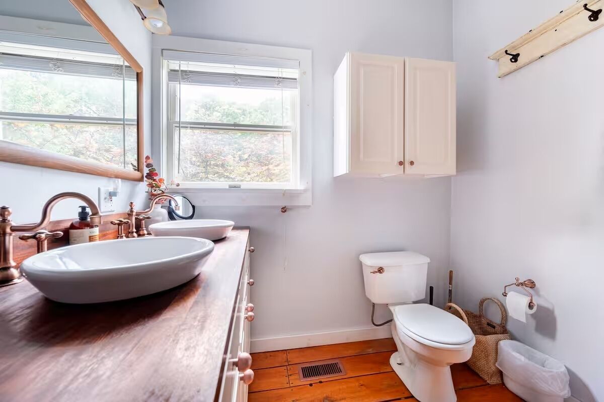 Een badkamer met een houten wastafelmeubel, een witte wasbak en toilet.